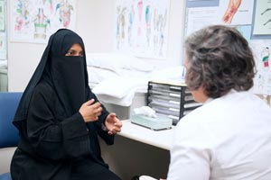 Woman in burqa talking to health professional