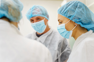 Three people wearing surgical masks and hair nets
